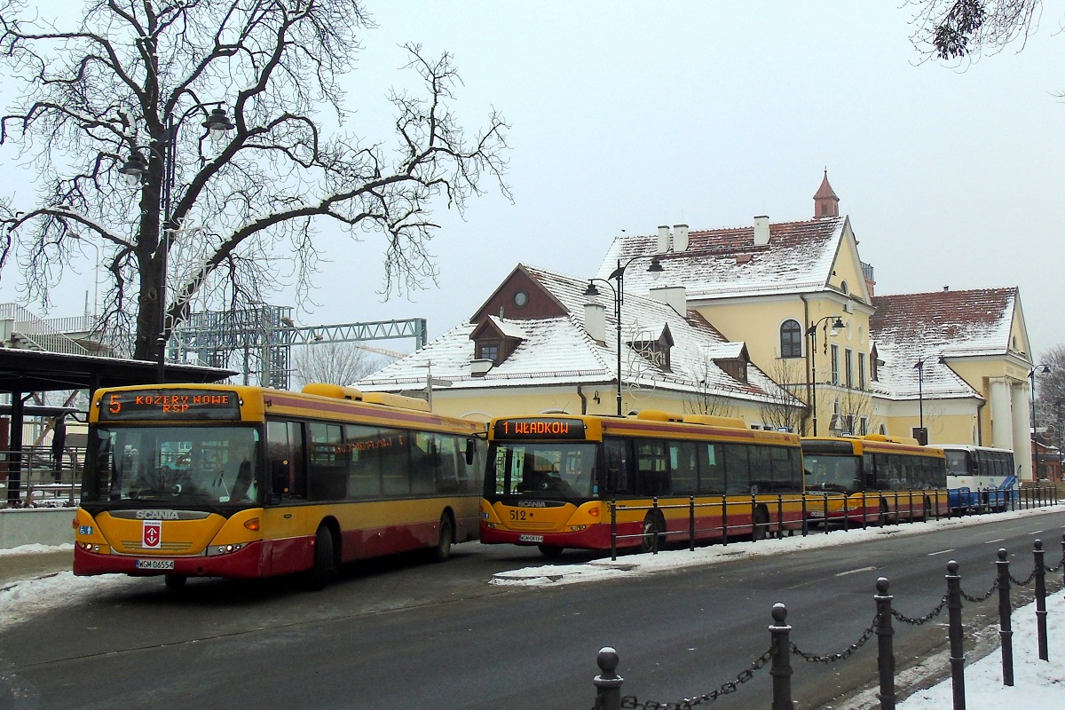 70241
Scania #70241 (ex. A541) wyjeĹźdĹźa z zatoczki autobusowej pod widocznym w tle dworcem PKP jadÄc w obsĹudze kursu "5857" linii numer 5 w relacji Grodzisk Maz. Dw. PKP (9:46)-Kozery Nowe PÄtla (10:15). Obok stoi Scania o numerze 70212 (ex. A512) po zakoĹczeniu obsĹugi kursu linii numer 2 w relacji KsiÄĹźenice PÄtla (8:50)-Grodzisk Maz. Dw. PKP (9:15). NastÄpnie pojedzie w obsĹudze kursu "5007" linii numer 1 w relacji Grodzisk Maz. Dw. PKP (10:05)-WĹadkĂłw PÄtla (10:22). Za niÄ kolejna Scania (tym razem z numerem 70252 (ex. A552)) po zakoĹczeniu obsĹugi kursu linii numer 4 w relacji Radonie PÄtla (9:05)-BoĹźa Wola (9:54) p. Grodzisk Maz. Dw. PKP (9:20) - od PKP obsĹugÄ kursu przejÄĹ Vehixel Cytios #50024. Na samym koĹcu stoi HadziewiÄtka o numerze 40140 oczekujÄca na zjazd na zajezdniÄ po zakoĹczeniu obsĹugi kursu "132" linii podmiejskiej w relacji Grzegorzewice (9:00)-Grodzisk Maz. Dw. PKP (9:39).
W owym czasie spotkanie 3 Scanii pod grodziskim dworcem PKP naleĹźaĹo do rzadkoĹci - obecnie taki widok jest niemal codziennoĹciÄ. 

